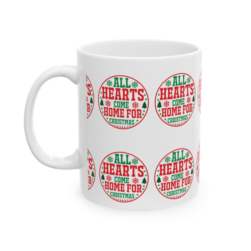 White ceramic mug decorated with repeating red and green circular Christmas-themed logos that say ’All Hearts Come Home For Christmas’