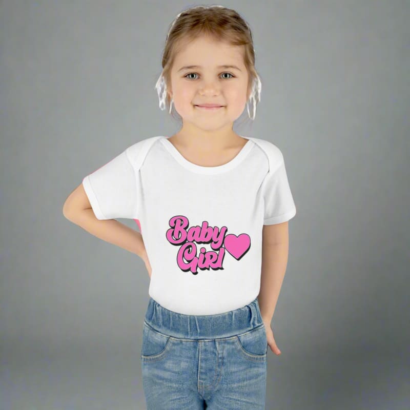 Young child wearing a white t-shirt with ’Baby Girl’ printed on it and blue jeans.