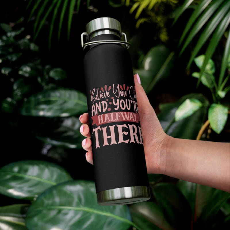 Black water bottle with pink inspirational text against a leafy background.