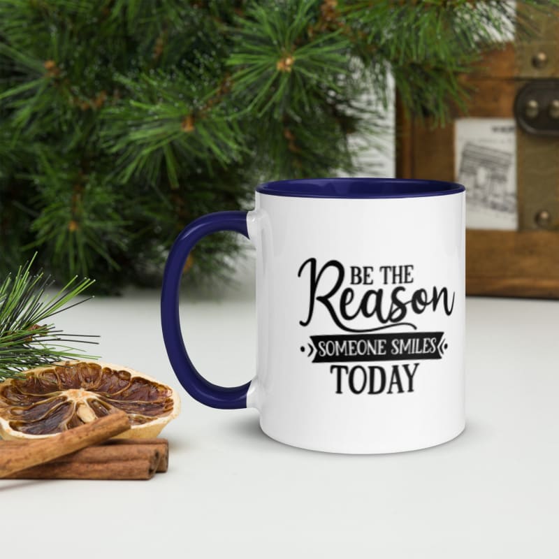 White mug with blue handle featuring the motivational text ’Be the Reason Someone Smiles Today’.