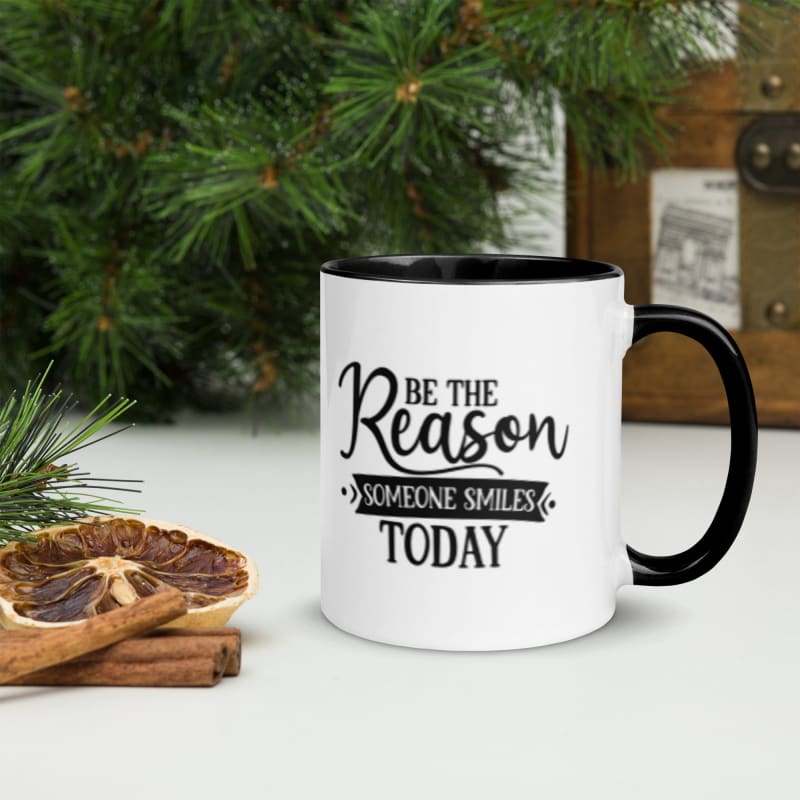 White coffee mug with black handle and inspirational text saying ’Be the Reason Someone Smiles Today’.