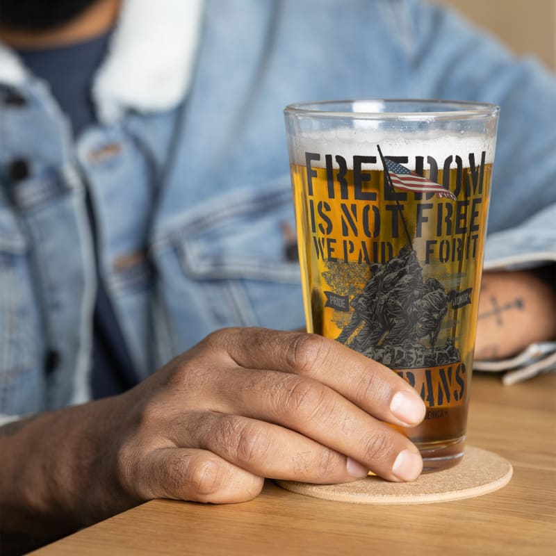 Glass of beer with text printed on it about freedom not being free.