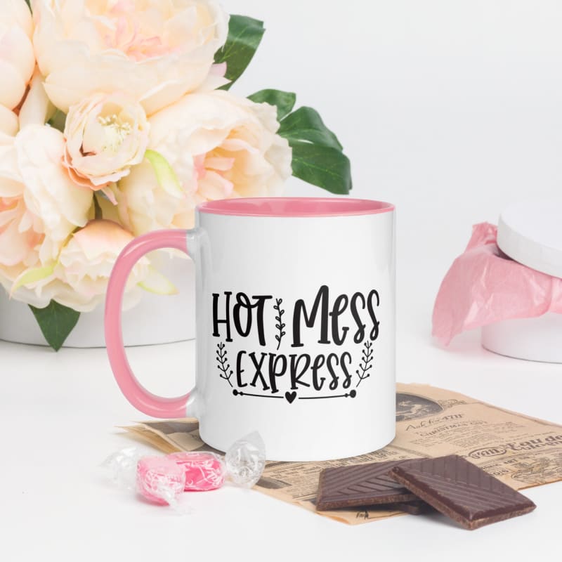 White mug with pink handle and rim featuring the text ’Hot Mess Express’ in black lettering.