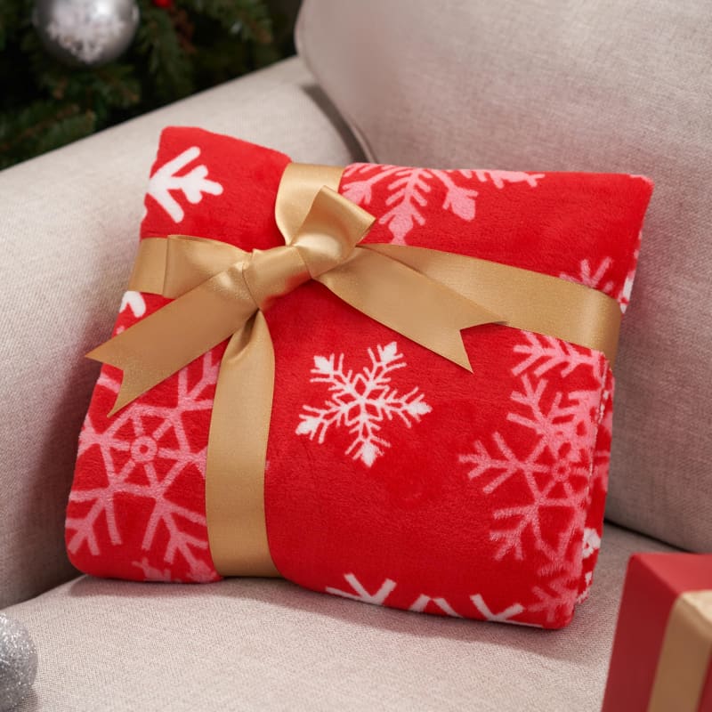 Red snowflake-patterned blanket wrapped with a gold bow.