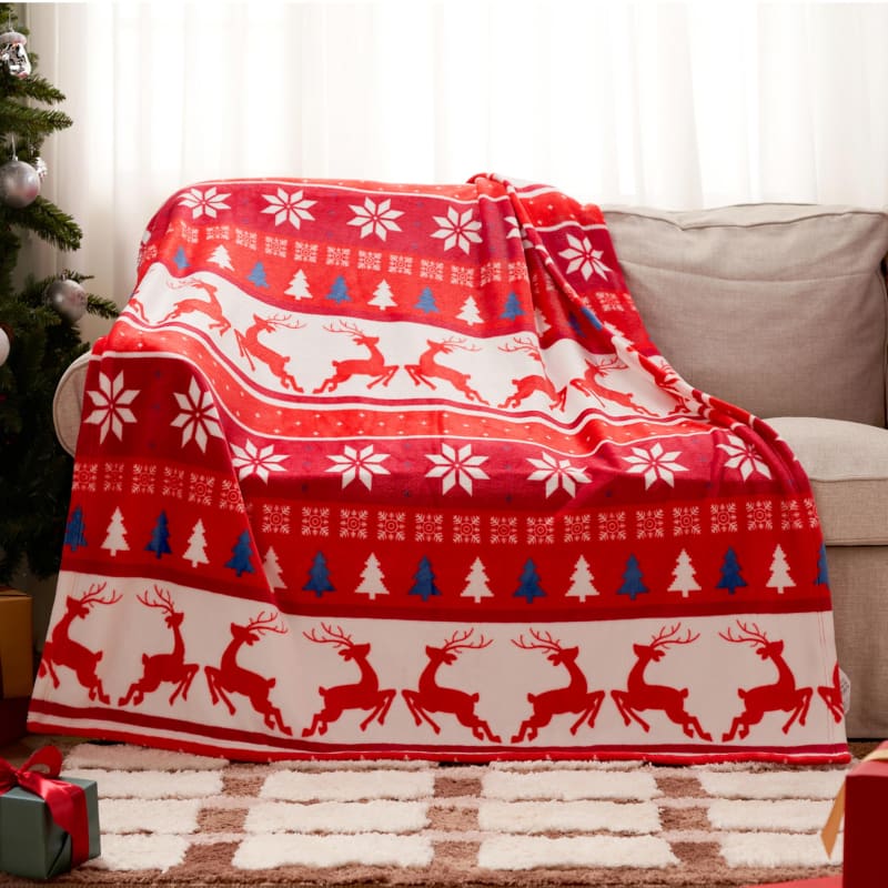 Red and white holiday throw blanket with reindeer and snowflake patterns.