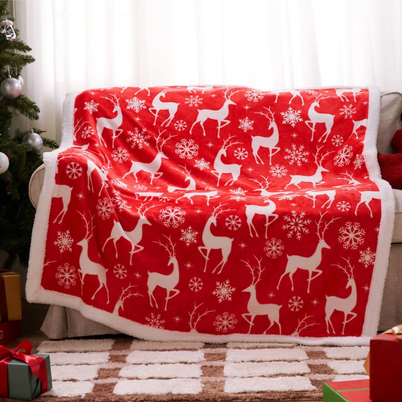 Red and white fleece blanket with reindeer and snowflake pattern.