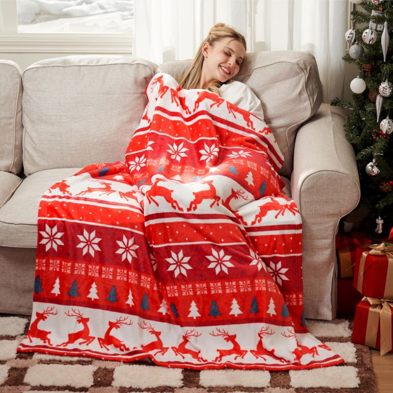 Red and white Nordic-patterned holiday blanket with reindeer and snowflake designs.