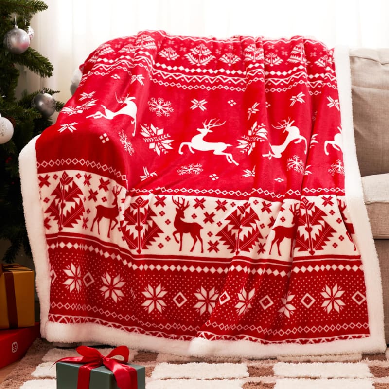 Red and white fleece throw blanket with Nordic reindeer and snowflake pattern.