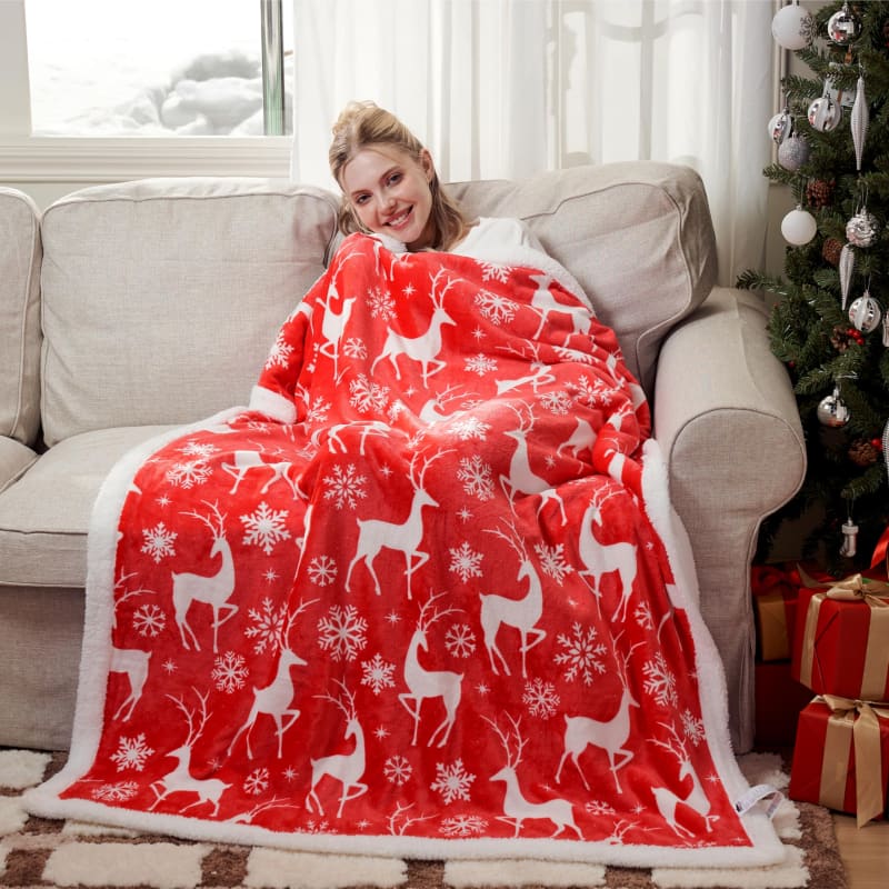 Red and white holiday blanket with reindeer and snowflake pattern.