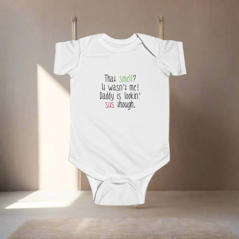 White baby onesie with humorous text about smells printed on the front.