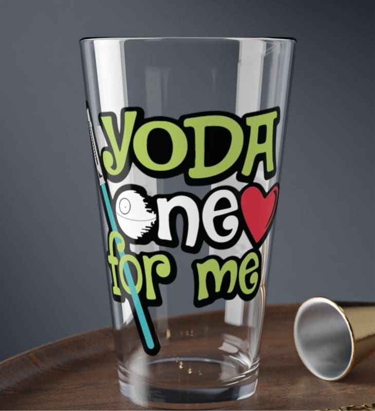 Glass drinking cup with colorful ’Yoda one for me’ text and Star Wars-themed graphics.