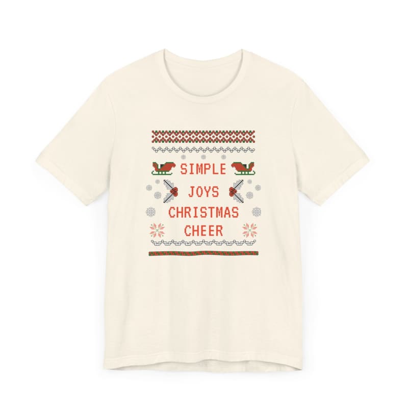 Cream-colored t-shirt featuring a Christmas-themed cross-stitch design with text ’Simple Joys Christmas Cheer’ and decorative birds.