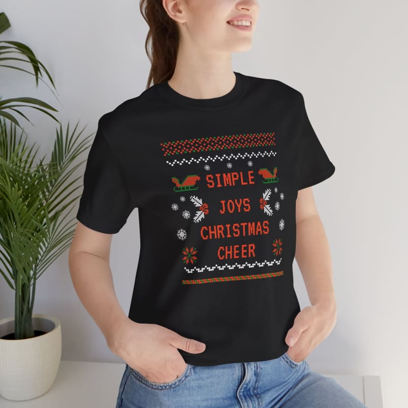 Black t-shirt featuring an ugly Christmas sweater design with ’Simple Joys Christmas Cheer’ text and holiday motifs.