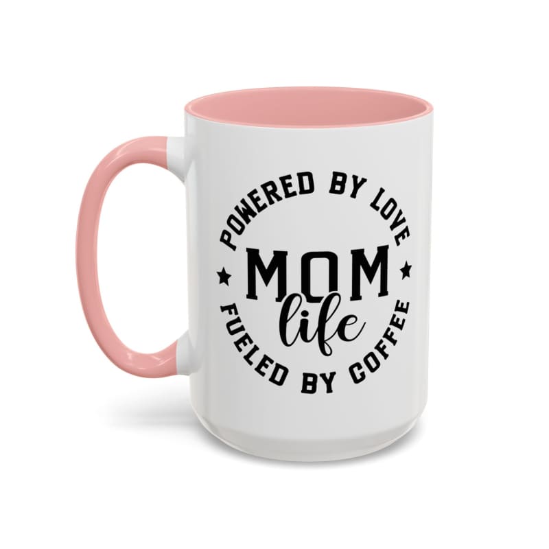 White coffee mug with pink handle and interior featuring black text that reads ’POWERED BY LOVE MOM LIFE FUELED BY COFFEE’